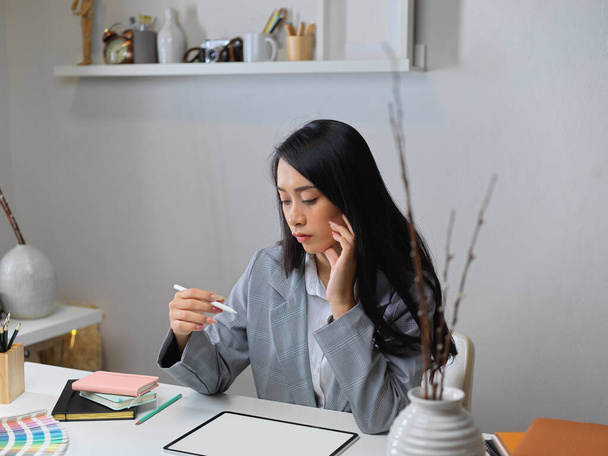 Πορτρέτο της επιχειρηματία σκέφτεται το έργο της, ενώ εργάζεται με mock up tablet στο γραφείο - Φωτογραφία, εικόνα