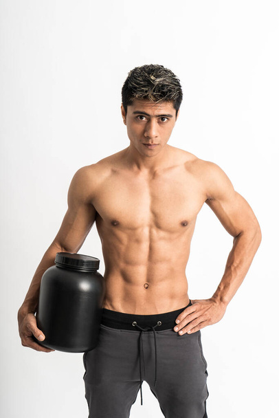 young man with muscular body carry a large bottle with one hand stand facing forward and look to camera - Foto, Imagen