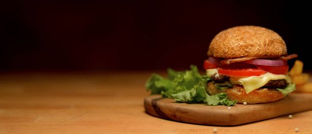 Close up widok świeżego pysznego hamburgera domowej roboty z frytkami służącymi na drewnianej tacy w restauracji - Zdjęcie, obraz