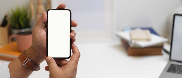 Zblízka pohled mužského podnikatele zobrazující prázdné obrazovky smartphone s rozmazaným kancelářským pozadím - Fotografie, Obrázek