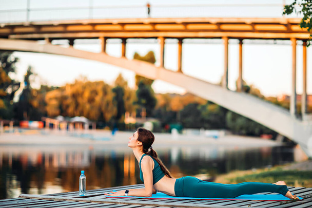 Deportiva hacer yoga en plataforma de madera - Foto, imagen
