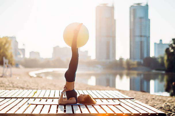 Sportowiec uprawia jogę z piłką fitness o wschodzie słońca - Zdjęcie, obraz