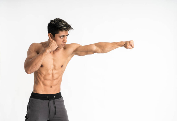 young man with muscular body with attacking movement with one hand punch - Foto, afbeelding