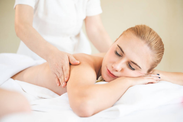 Health care and thai massage. Beautiful woman getting back and shoulder massage in spa salon - Photo, image