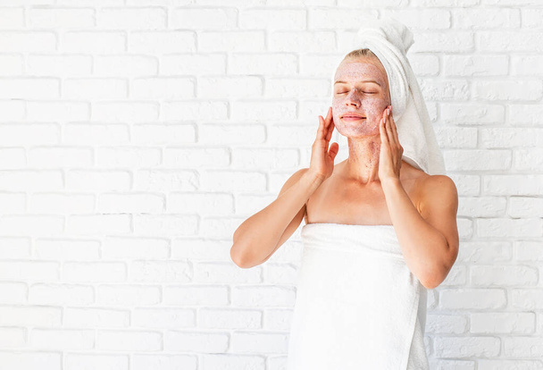 atrakcyjna uśmiechnięta kobieta nakładająca fartuch na skórę. Koncepcja oczyszczania twarzy. Spa i piękno. Kosmetyki naturalne - Zdjęcie, obraz
