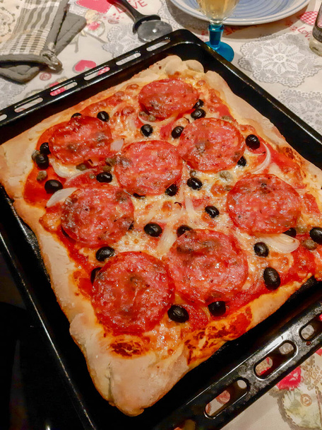 suggestiva immagine di una pizza fatta in casa con salumi piccanti, olive nere, pomodori e mozzarella - Foto, immagini