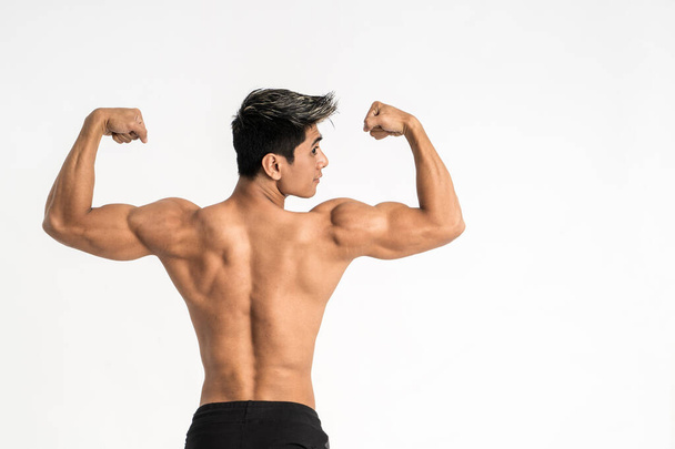 half body image of young man showing muscular body stand facing back - Foto, afbeelding