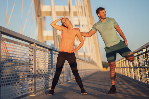 Jeune couple fait de l'exercice en plein air sur le pont dans la ville. - Photo, image