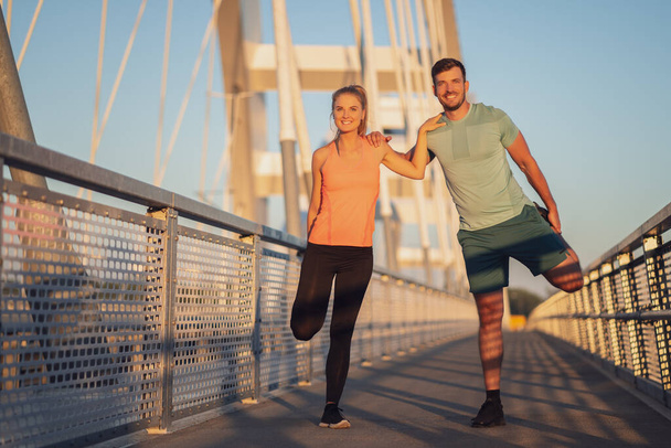 Young couple is exercising outdoor on bridge in the city. - Photo, Image