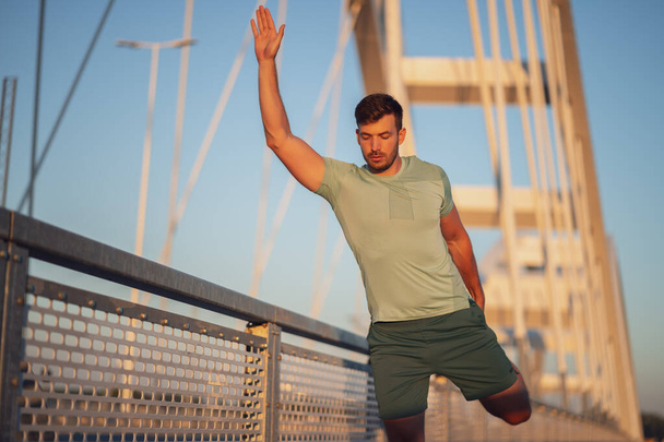 Young man is exercising outdoor on bridge in the city. - Foto, Imagem