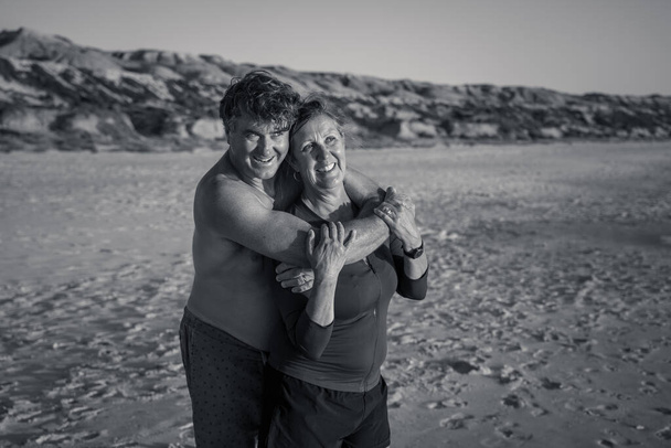Szabadtéri portré egy boldog érett párról, akik szerelmesek az üres, távoli tengerparton. Férfiak és nők együtt élvezik a szabadban az életstílust a kabáton. Aktív valódi emberek, nyaralás, utazás és menekülés. - Fotó, kép