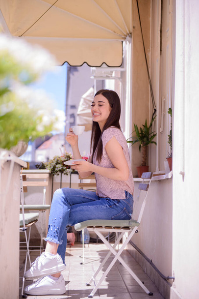 Young girl enjoying her coffee on a beautiful balcony - Valokuva, kuva