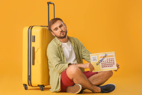 Smutný muž drží kalendář s psaným slovem QUARANTINE na barevném pozadí. Koncept dovolené - Fotografie, Obrázek