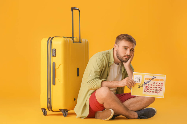 色の背景に書かれた単語QUARANTINEとカレンダーを保持悲しい男。休暇の概念 - 写真・画像