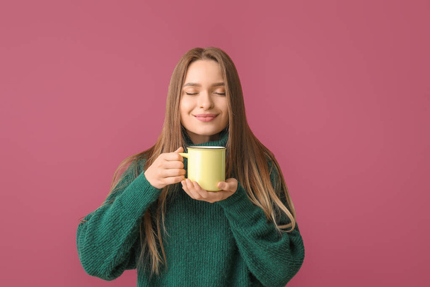 Mooie jonge vrouw met kopje thee op kleur achtergrond - Foto, afbeelding