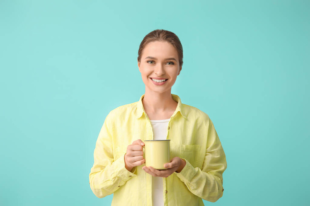 Beautiful young woman with cup of tea on color background - Foto, Bild