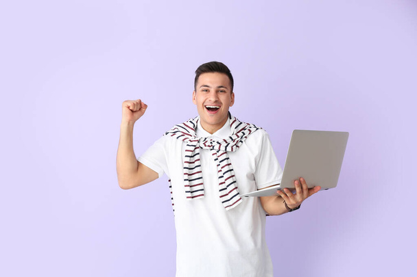 Programador masculino feliz con el ordenador portátil en fondo de color - Foto, Imagen