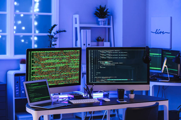 El puesto de trabajo moderno del programador en la oficina por la noche - Foto, Imagen
