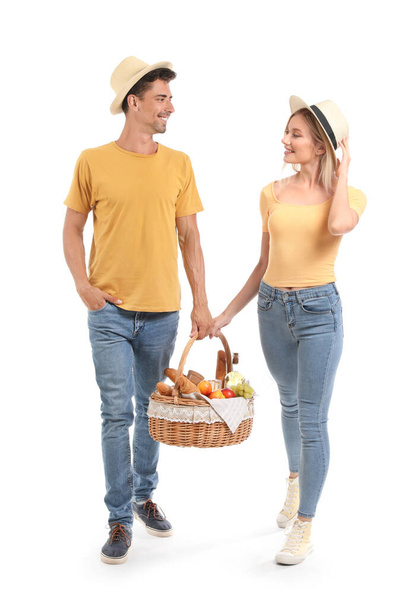 Young couple with food for picnic in basket on white background - Φωτογραφία, εικόνα