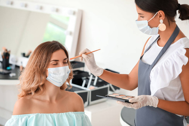 Female makeup artist working with client in salon during coronavirus epidemic - Zdjęcie, obraz