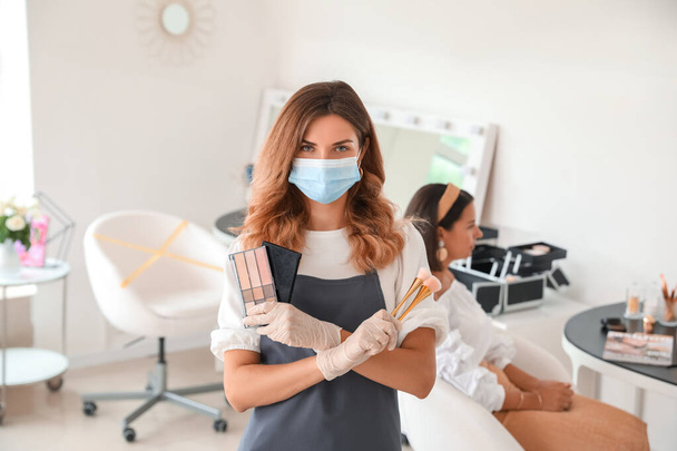 Artista de maquillaje femenina con máscara médica en el salón durante la epidemia de coronavirus - Foto, imagen