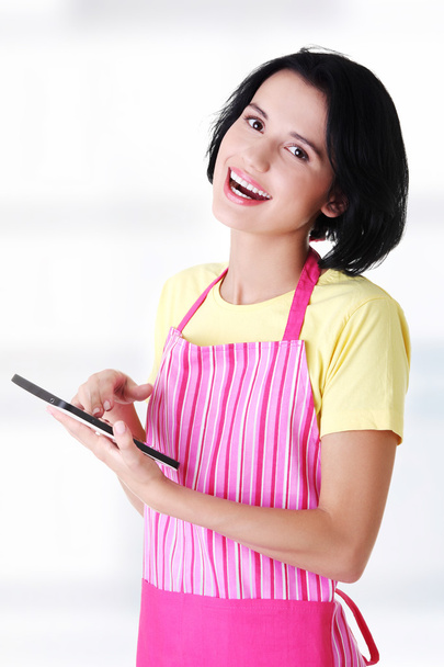 Young woman in pink apron using tablet computer - Foto, Imagen