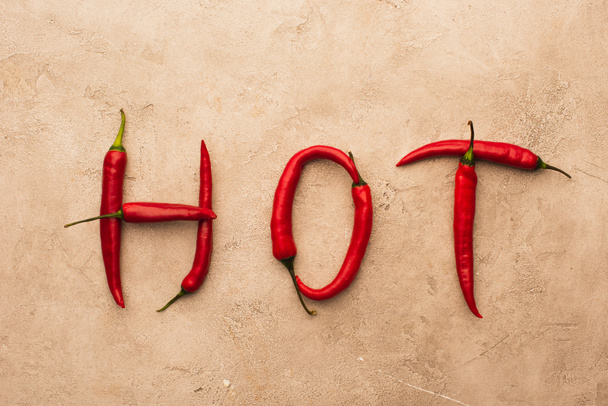 top view of word hot made of chili peppers on beige concrete surface - Fotografie, Obrázek