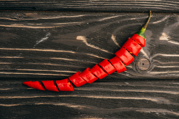 top view of sliced red chili pepper on wooden surface - Foto, Imagen