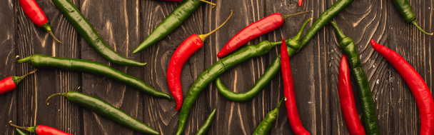 top view of red chili peppers and green jalapenos on wooden surface, panoramic shot - Photo, image