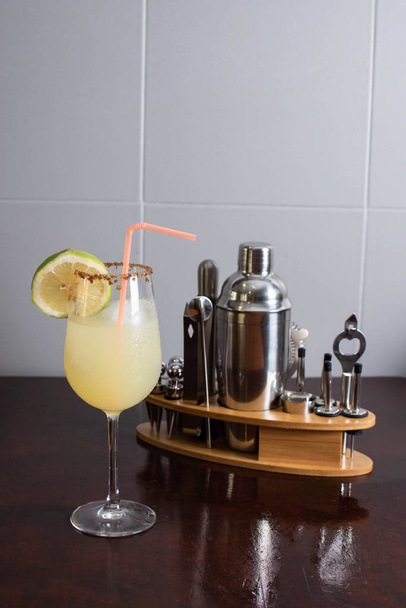 лимонный коктейль рядом с различными коктейльными инструментами - Фото, изображение