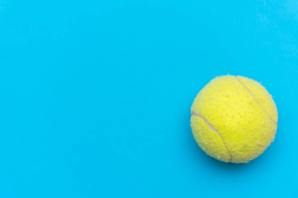 Jasnożółta piłka tenisowa na jednolitym tle aqua blue flat lay symbolizująca sport i aktywność z przestrzenią do kopiowania. - Zdjęcie, obraz