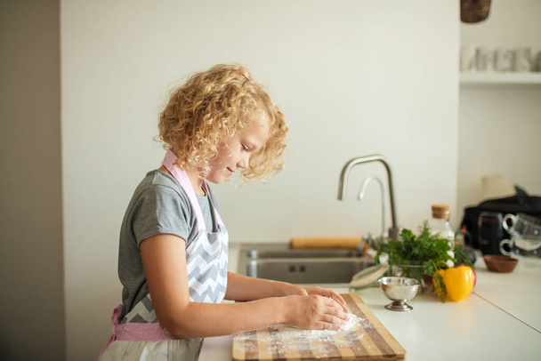Woman and cute daughter cooking on kitchen, making dough for birthday party. - Foto, afbeelding
