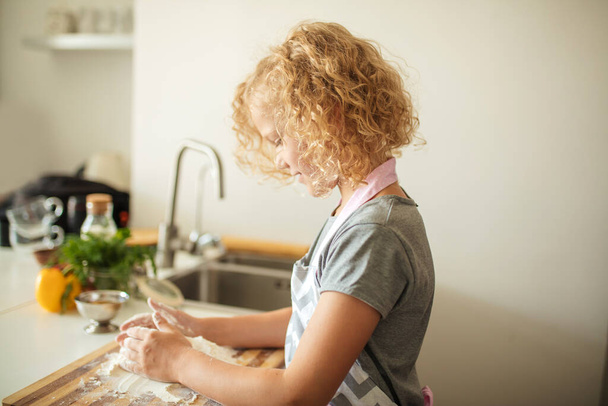 Woman and cute daughter cooking on kitchen, making dough for birthday party. - 写真・画像
