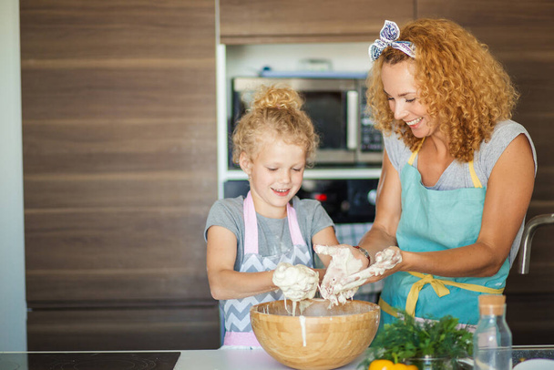 Mother and child daughter girl having fun while making dinner at the kitchen. - Foto, imagen