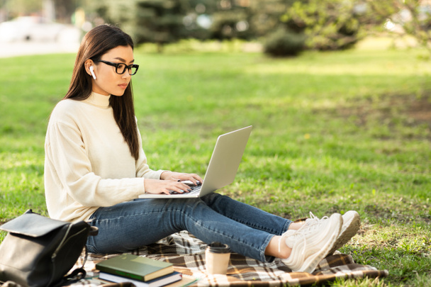 Asiatico donna utilizzando laptop, lavorando nel parco - Foto, immagini