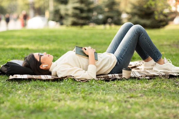 Menina deitada na grama quente verão, ouvindo música ro
 - Foto, Imagem