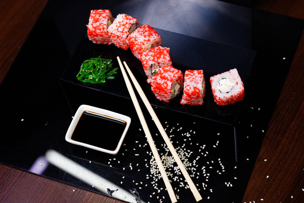 Sushi mit Lachs. Sojasauce, roter Kaviar. Sushi auf schwarzem Hintergrund. - Foto, Bild
