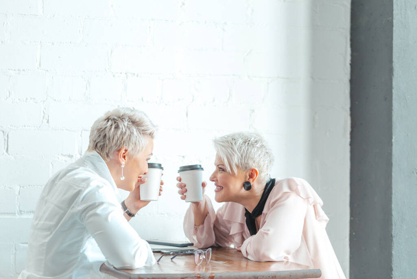 Two female senior collegues sitting next to each other in an cafe - Fotoğraf, Görsel