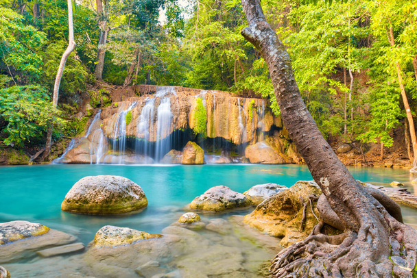 Tropische Landschaft mit wunderschönem Wasserfall, smaragdgrünem See, Felsen und großen Baumwurzeln im wilden Urwald. Erawan Nationalpark, Kanchanaburi, Thailand - Foto, Bild
