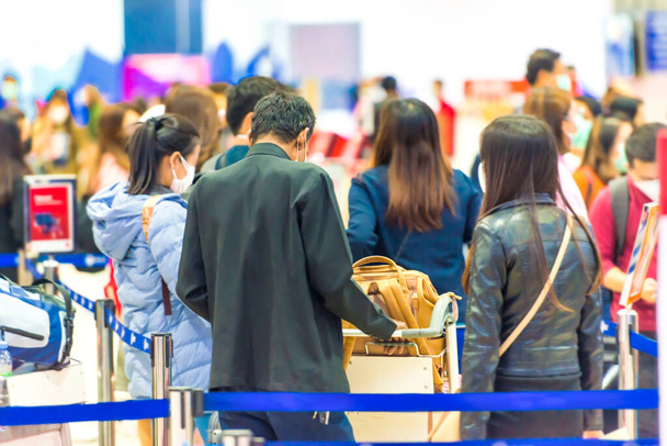 Толпа людей с багажом ждет в очереди в аэропорту во время карантина коронавируса - Фото, изображение
