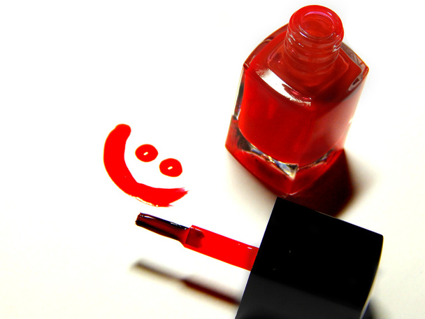 Esmalte de uñas rojo, cepillo y una cara sonriente
 - Foto, imagen