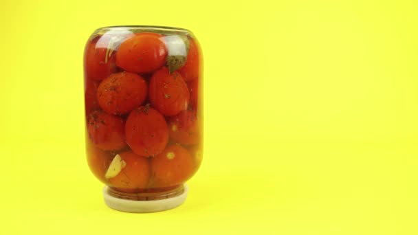 Overturned glass jar of closed tomatoes on a yellow background - Felvétel, videó