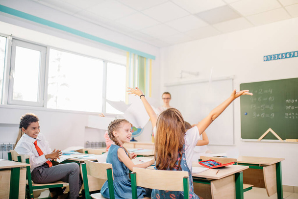 school kids have fun in class and throwing paper in air - Foto, Bild