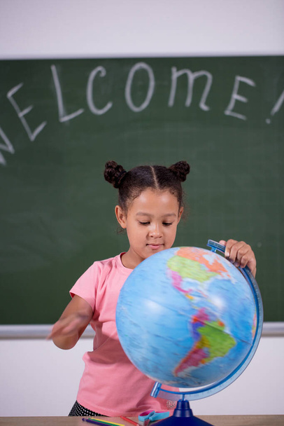 african schoolgirl looking globe with chalk background - 写真・画像