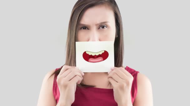 Azjatka w czerwonej koszuli trzymając brązowy papier z żółtymi zębami rysunek jego usta na szarym tle, nieświeży oddech lub cuchnący oddech, Koncepcja z dziąseł opieki zdrowotnej i zębów - Materiał filmowy, wideo