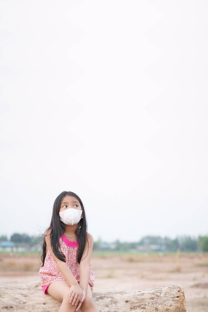 Asian child new idea think or kid girl wear N95 face mask and sick with flu cough sneeze for protect covid-19 virus or PM 2.5 dust by smoke or air and close mouth nose to unhappy look above with space - Photo, Image