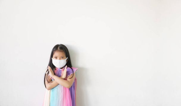 アジアの子供クロス腕や子供の女の子の強い摩耗N95布顔マスクのための緊密な口の鼻と戦い病気でインフルエンザ咳や保護PM 2.5ほこりやインフルエンザのカバー19コロナウイルスホワイトスペースの背景 - 写真・画像