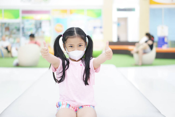 Азійська дитина або дівчинка носить маску обличчя N95 і хвора на ніс з холодним кашлем і чхає для доброго захисту вірусу грипу або PM2.5 пилу на повітрі і бактерій від диму і роту в школі. - Фото, зображення