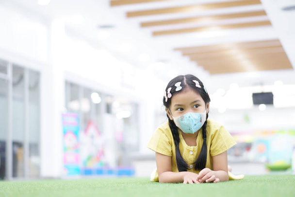 Азиатская девочка или девочка носят маску N95 бумагу для лица и болеют на носу с холодным кашлем и чихают для защиты PM2.5 пыли или вируса гриппа и загрязнения воздуха бактерии от дыма с закрытым ртом в школе - Фото, изображение