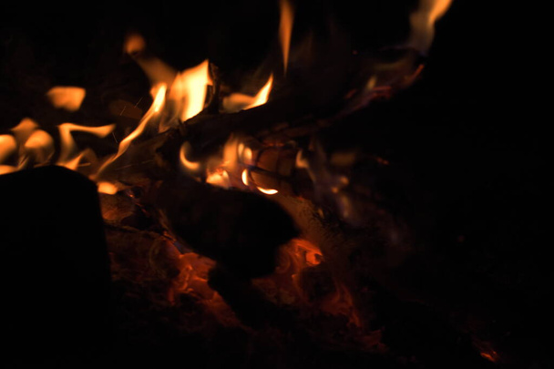 Καίγοντας ξύλα τη νύχτα. Κατασκήνωση στην τουριστική κατασκήνωση στη φύση στα βουνά. Φλόγα και φωτιά σπινθήρες σε σκοτεινό αφηρημένο φόντο. Μαγείρεμα μπάρμπεκιου. Στοιχείο φωτιάς της κόλασης. Καύσιμα, ισχύς και ενέργεια - Φωτογραφία, εικόνα